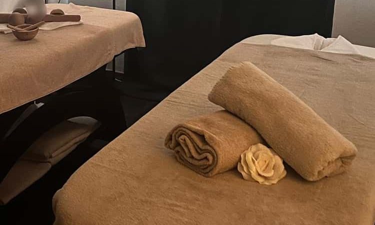 A tranquil massage setup featuring neatly arranged towels and a flower on a massage table.